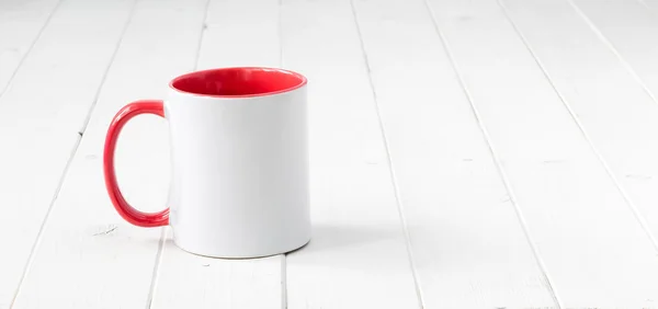 Weißer Becher mit rotem Henkel und innen auf dem Tisch — Stockfoto