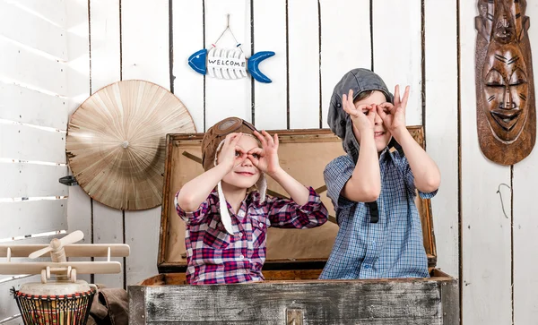 Deux petits enfants dans des chapeaux pilotes faisant des lunettes avec les mains — Photo