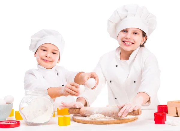 Dos pequeños cocineros divertidos preparando la masa —  Fotos de Stock