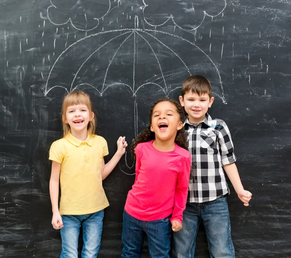 Drei lustige Kinder mit Regenschirm an der Tafel gezeichnet — Stockfoto