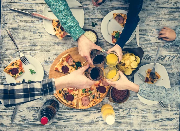 People clanging glasses together having pizza — Stock Photo, Image