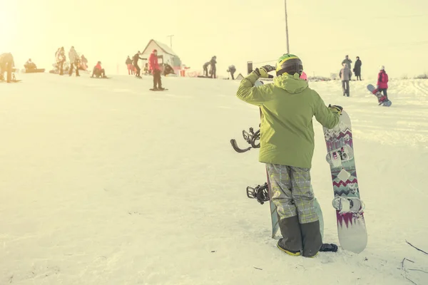 Людина в лижному костюмі зі сноубордами дивиться на пагорб — стокове фото