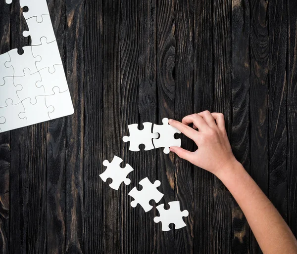 Mano inizia a raccogliere pezzi di puzzle — Foto Stock