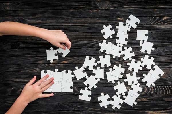 Hands starting to collect puzzle pieces — Stock Photo, Image