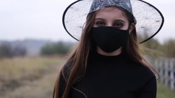 Dziewczyna w kapeluszu czarownicy i masce ochronnej — Wideo stockowe