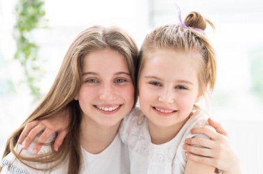 Sevimli gülümseyen kız kardeşler kucaklaşır