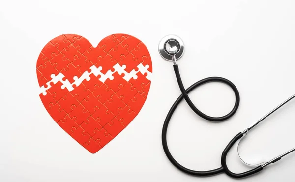 Stethoscope next to heart shaped puzzle — Stock Photo, Image