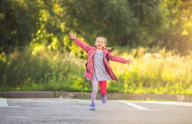 Mutlu küçük kız okuldan sonra koşuyor.