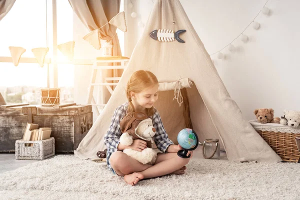 Niña explorando globo con oso de peluche — Foto de Stock