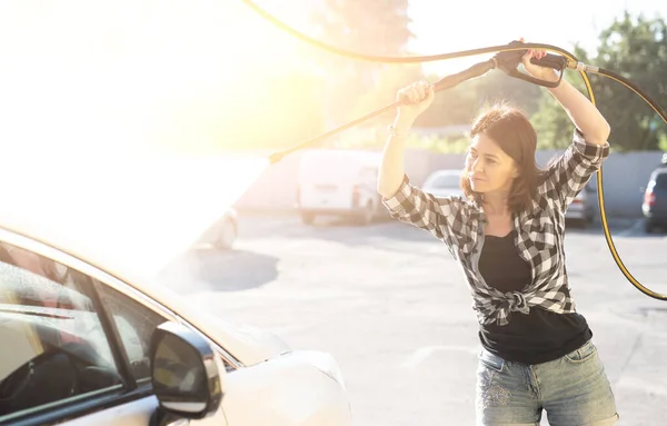Kadın arabanın camını suyla temizliyor. — Stok fotoğraf