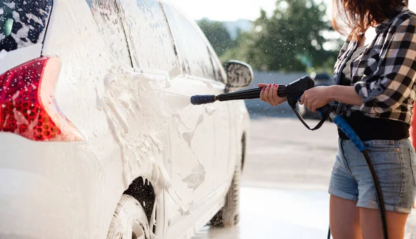 Kız arabayı köpük spreyiyle yıkıyor. — Stok fotoğraf