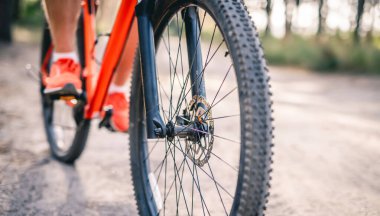 Bisiklet süren spor ayakkabılı adamın bacakları.