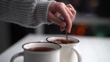 Beyaz kupada kakao karıştıran kadın.