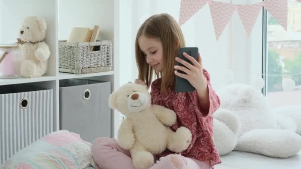 Lächelndes kleines Mädchen macht Selfie mit dem Smartphone — Stockvideo