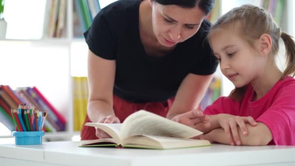 Meisje lezen boek onder toezicht van de leraar — Stockvideo