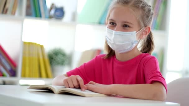 Malá dívka v ochranné masce s učebnicí — Stock video