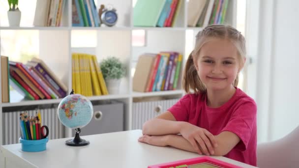 Leende liten flicka sitter vid skolbänken — Stockvideo