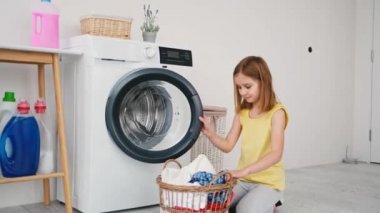 Çamaşır makinesine çamaşır yükleyen küçük kız.