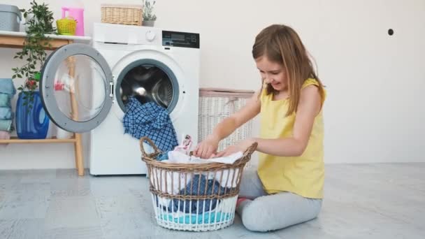 Menina jogando roupas na máquina de lavar roupa — Vídeo de Stock