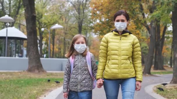 마스크를 쓴 어머니와 함께 걷고 있는 어린 소녀 — 비디오