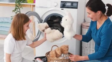 Anne ve kızı oyuncakları makineye yüklüyor.