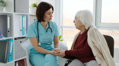 Klinikte kıdemli bir kadınla konuşan terapist.