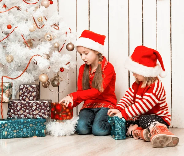 Duas meninas abrem presentes de Natal sentadas no chão — Fotografia de Stock