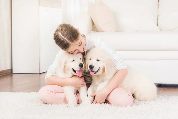 Fille s'asseoir étreignant chiots récupérateur — Photo