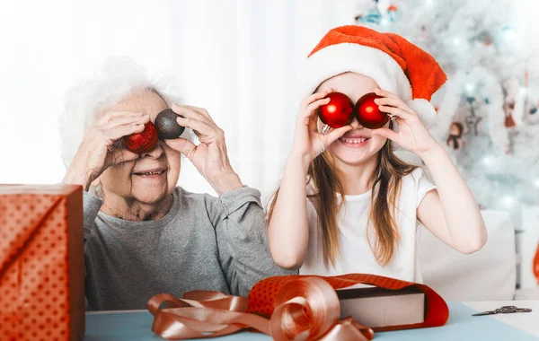 Nieta sosteniendo bolas decorativas con la abuela — Foto de Stock