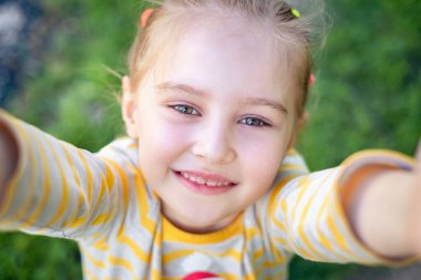 Küçük kız parkta selfie çekiyor.