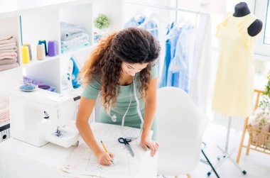 Örgü kadın kumaşa çizim yapıyor.