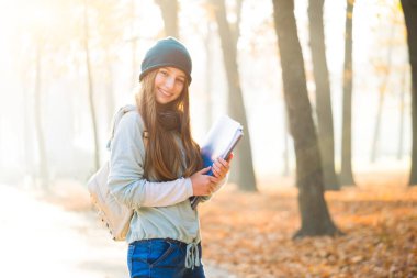 Sonbahar parkında sevimli bir öğrenci.