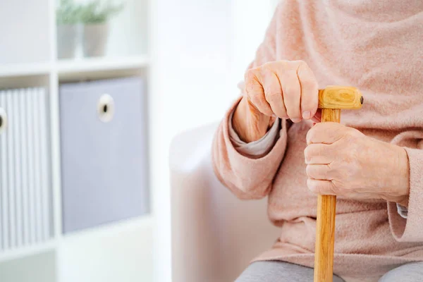 Manos de anciana sosteniendo bastón — Foto de Stock