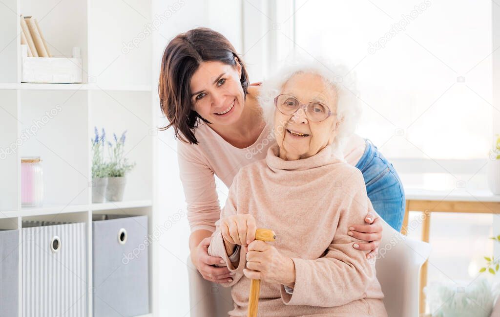Elderly woman embraced by daughter