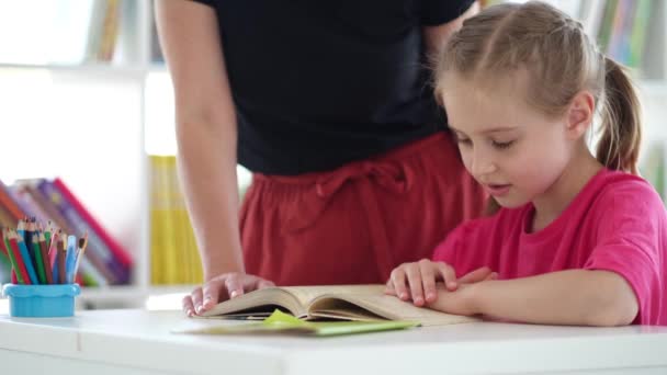 Gadis kecil membaca buku di bawah pengawasan guru — Stok Video