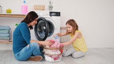 Anne ve kızı yıkanmak için kıyafet yüklüyorlar.