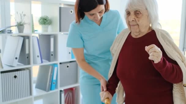 Verzorger helpt oudere vrouw om te lopen — Stockvideo
