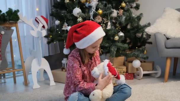 Menina colocando chapéu de Papai Noel no urso de pelúcia — Vídeo de Stock