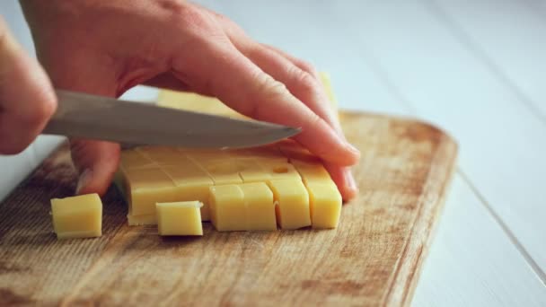Woman chops cheese into cubes — Stock Video