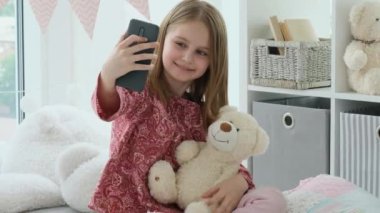 Gülümseyen küçük kız akıllı telefondan selfie çekiyor.