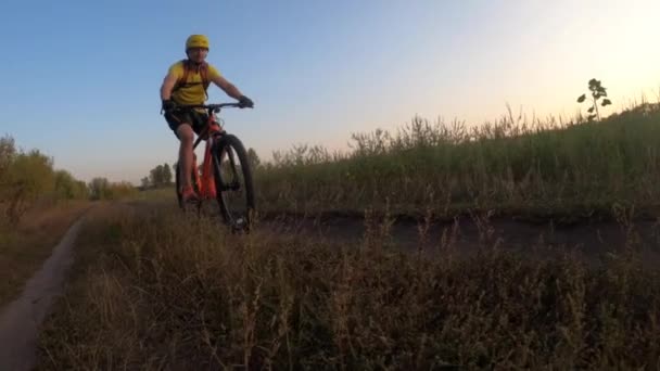 Hombre montar en bicicleta cerca del campo al atardecer — Vídeo de stock