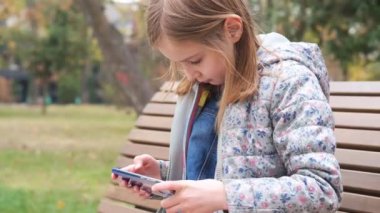 Küçük kız akıllı telefonda oyun oynuyor.