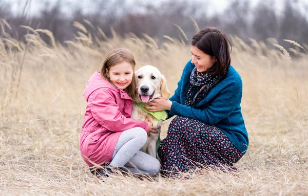 Девочка и женщина ласкают собаку — стоковое фото