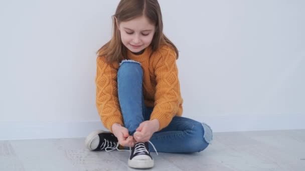 Happy little girl tying shoelace on sneakers — ストック動画