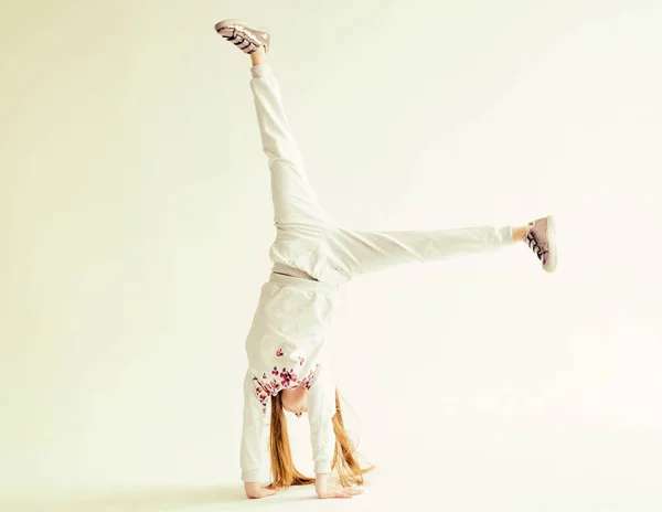 Aktivní holčička na bílém pozadí dělá handstand — Stock fotografie