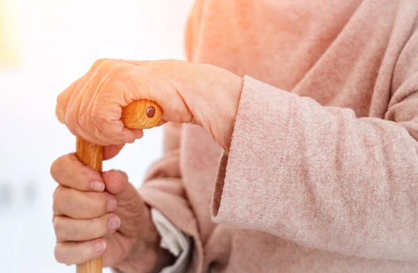 Manos de anciana sosteniendo bastón — Foto de Stock