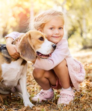 Küçük kız köpeğe sarılıyor.