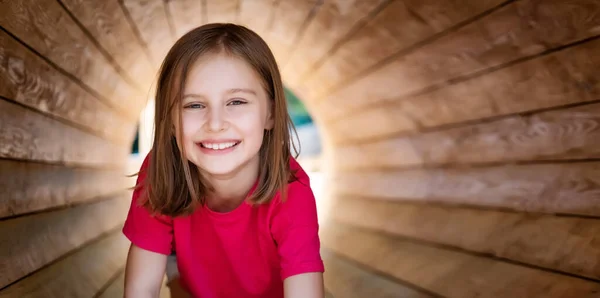 Улыбающаяся маленькая девочка в деревянной трубе — стоковое фото