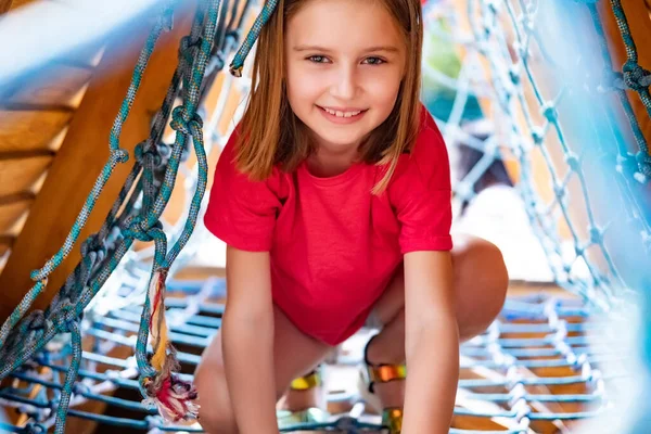 Liten flicka som leker på klätternät — Stockfoto