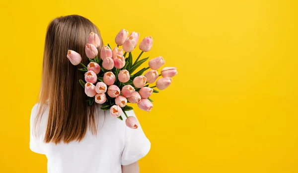 Mädchen mit Blumen isoliert auf gelbem Hintergrund — Stockfoto